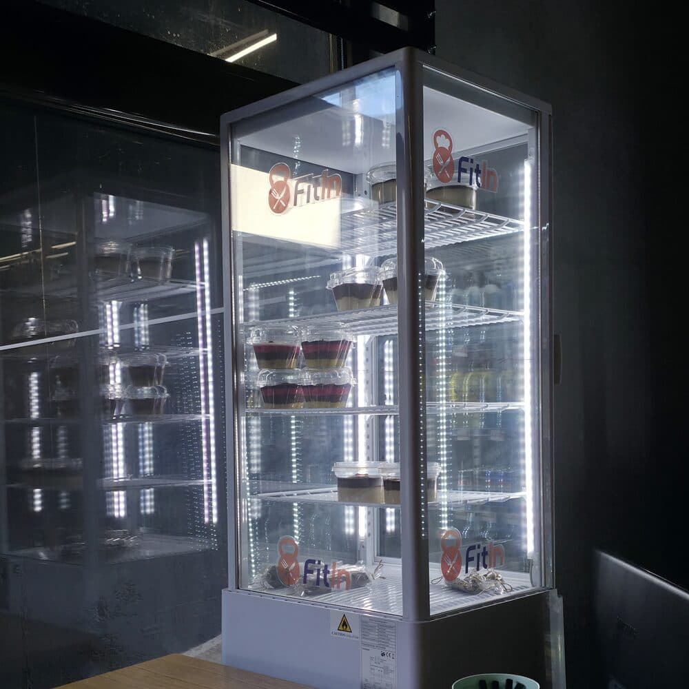 Osvetljena brendirana Fit In vitrina puna proteinskih kolača u objektu